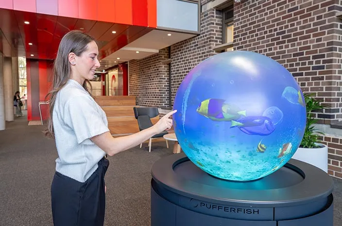 Visitor interacting with a PufferTouch sphere at Macquarie University