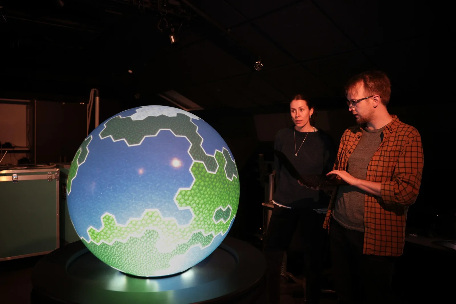 Two visitors exploring scientific content on a PufferTouch sphere at WISDOME