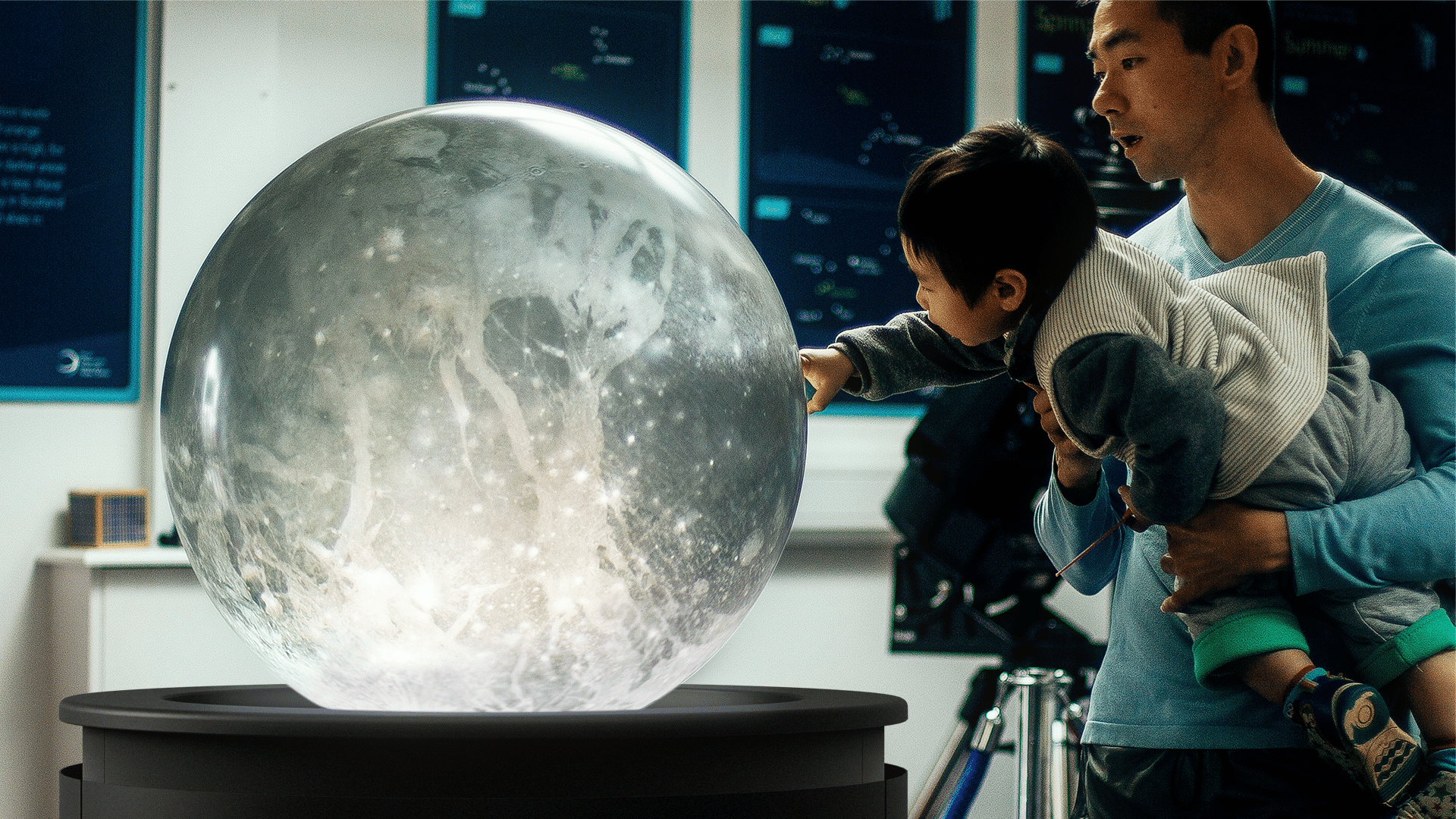 A father holds his son, both amazed by the appearance of the Moon on the PufferTouch