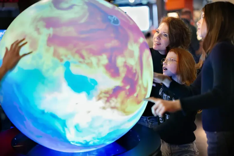 Children and adults exploring a PufferTouch sphere at NEMO Science Museum
